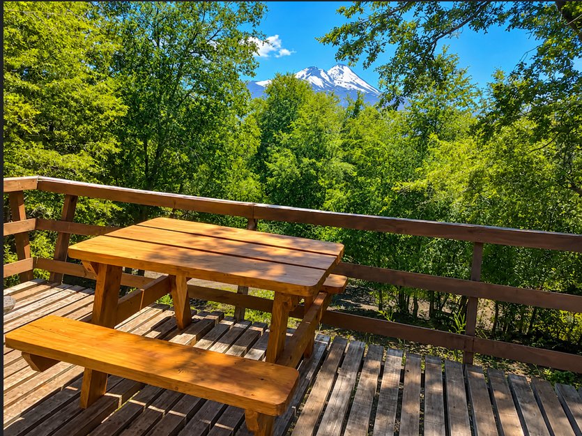 Terraza de la Cabaña Chercán con mesa de madera y vista al volcán Llaima